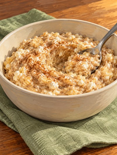 A spoon rests in thick banana and sunflower-butter mash with cottage-cheese curds and cinnamon.